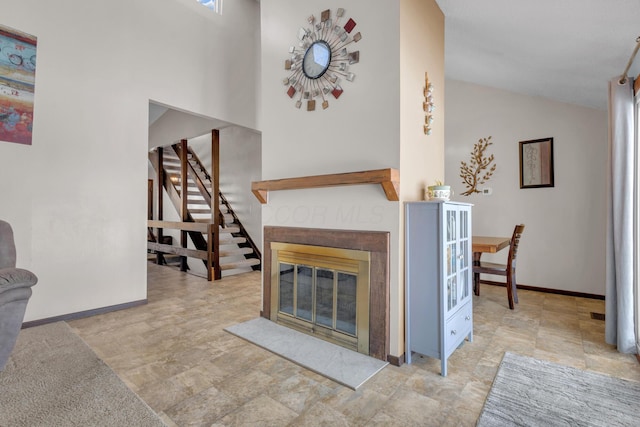 living room with stairway, a fireplace, baseboards, and vaulted ceiling