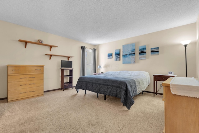 bedroom featuring light colored carpet, baseboards, and a textured ceiling