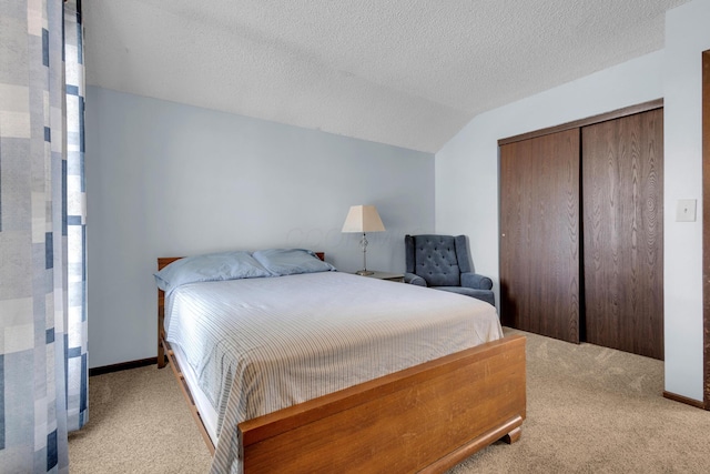 bedroom featuring baseboards, lofted ceiling, carpet floors, a closet, and a textured ceiling