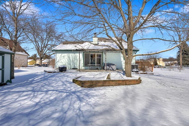 snow covered rear of property with a chimney