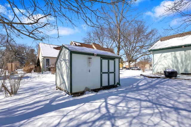 snow covered structure with an outbuilding and a storage shed