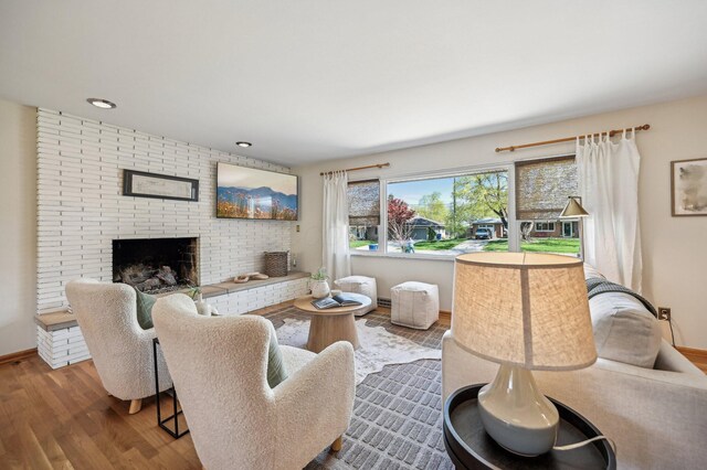 living room featuring a fireplace, wood finished floors, baseboards, and recessed lighting