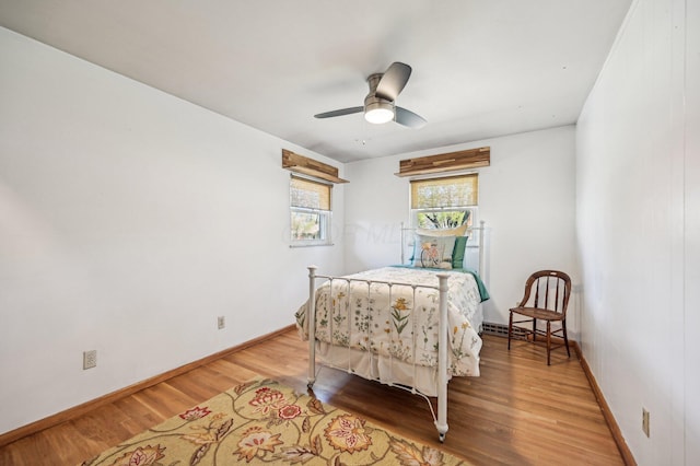 bedroom with light wood-type flooring, a ceiling fan, and baseboards