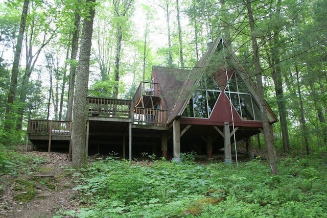 rear view of house featuring a deck and roof with shingles