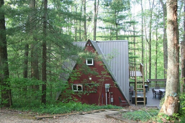 view of side of property featuring a standing seam roof, a wooden deck, and metal roof