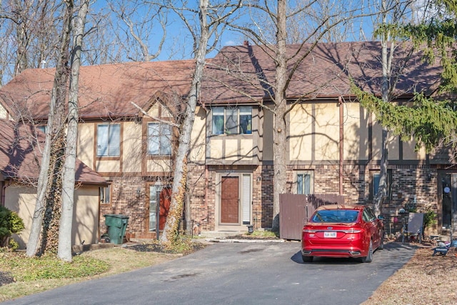 view of front facade with stucco siding, brick siding, and a shingled roof