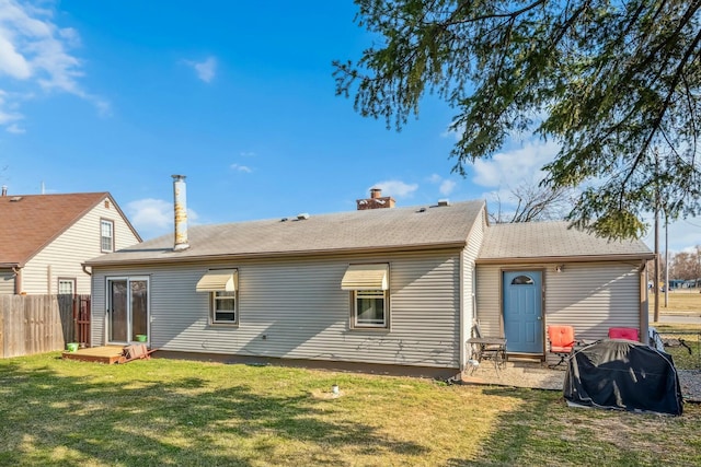 back of property with a lawn, a chimney, and fence