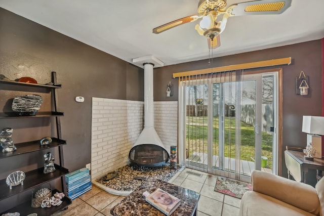 tiled living room featuring visible vents, a healthy amount of sunlight, a wood stove, and ceiling fan