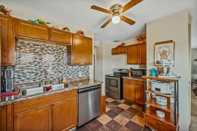 kitchen with backsplash, appliances with stainless steel finishes, brown cabinetry, a ceiling fan, and a sink