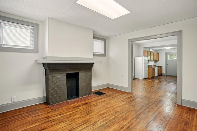 51 Hayden Ave, Columbus, OH 43222 - unfurnished living room with baseboards, hardwood / wood-style floors, a brick fireplace, and a drop ceiling