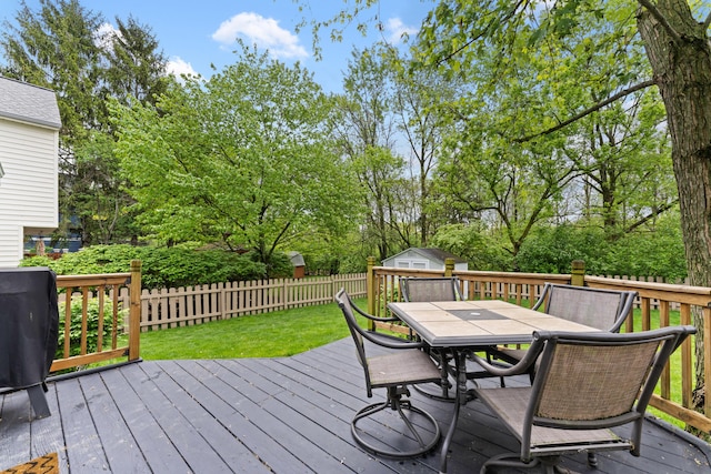 wooden deck featuring outdoor dining area, an outbuilding, and view of scattered trees