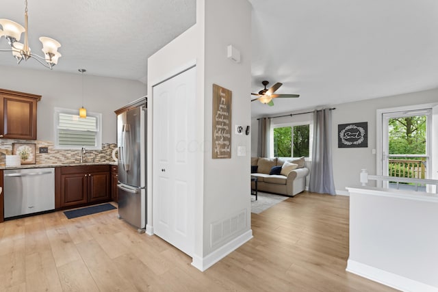 kitchen featuring appliances with stainless steel finishes, light wood-style floors, a ceiling fan, open floor plan, and vaulted ceiling