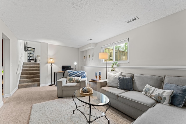 living area with carpet flooring, baseboards, stairs, and a textured ceiling