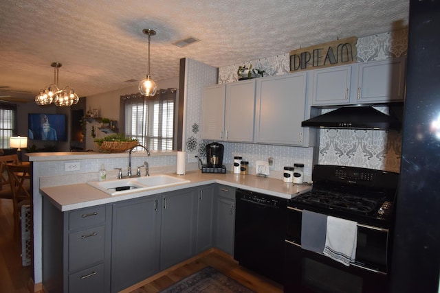 kitchen featuring gray cabinetry, under cabinet range hood, a peninsula, black appliances, and a sink