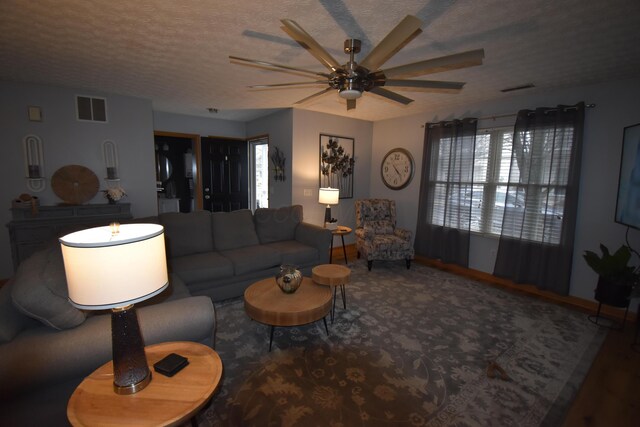 living room with a textured ceiling, visible vents, a wealth of natural light, and ceiling fan