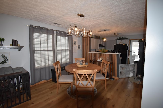 dining space with an inviting chandelier, light wood-style flooring, visible vents, and a textured ceiling