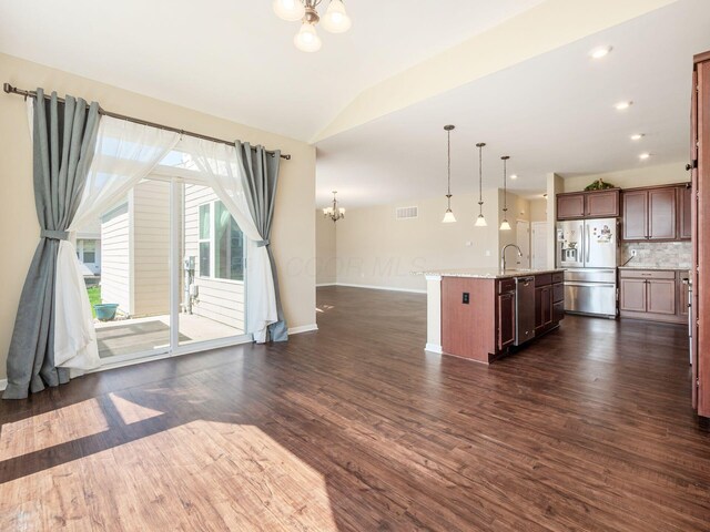 kitchen with fridge with ice dispenser, an inviting chandelier, open floor plan, lofted ceiling, and a sink