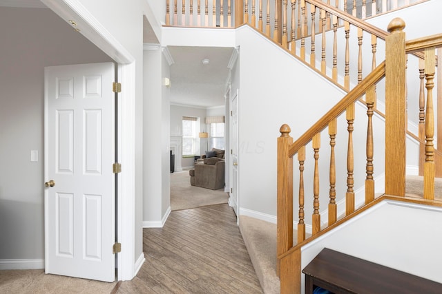 staircase with baseboards, ornamental molding, and wood finished floors
