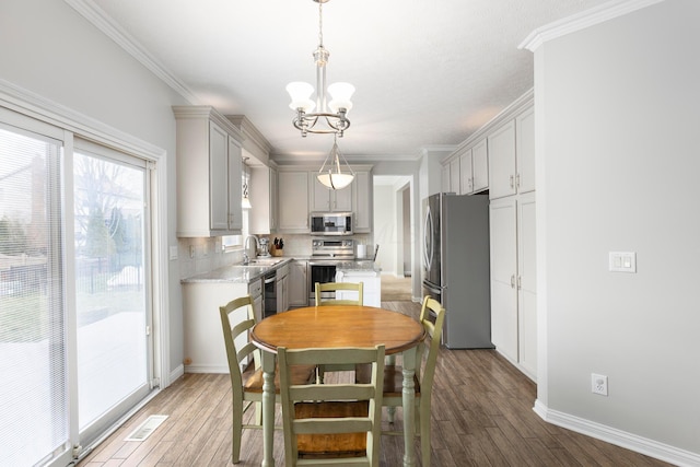 kitchen featuring light wood-style floors, light countertops, stainless steel appliances, and an inviting chandelier