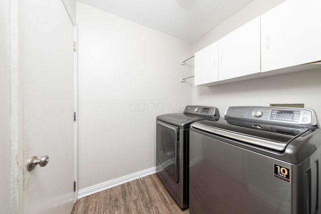 laundry area featuring baseboards, cabinet space, wood finished floors, and washer and clothes dryer