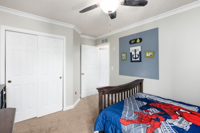 carpeted bedroom with crown molding, a textured ceiling, visible vents, a ceiling fan, and a closet