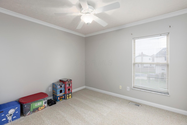 recreation room featuring visible vents, carpet, baseboards, ceiling fan, and ornamental molding