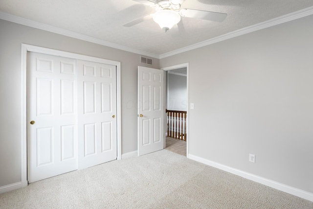 unfurnished bedroom with crown molding, carpet flooring, a textured ceiling, baseboards, and visible vents