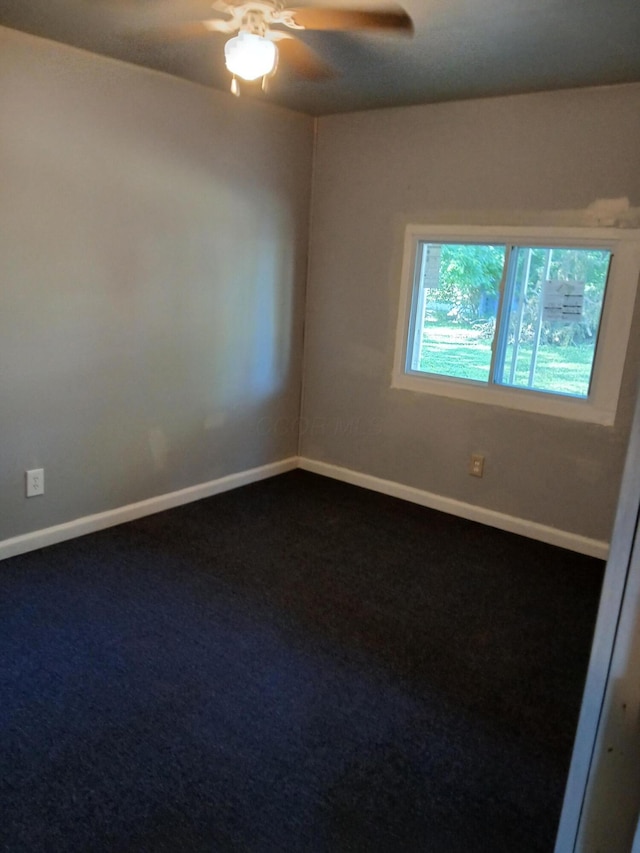 unfurnished room with baseboards, a ceiling fan, and dark carpet