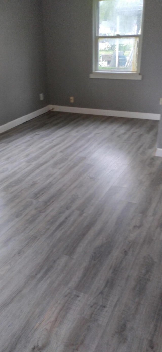 empty room with dark wood finished floors and baseboards