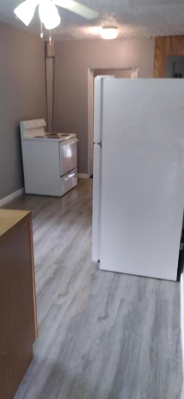 kitchen with ceiling fan, baseboards, white appliances, and wood finished floors