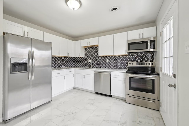 kitchen featuring a sink, marble finish floor, appliances with stainless steel finishes, and white cabinetry