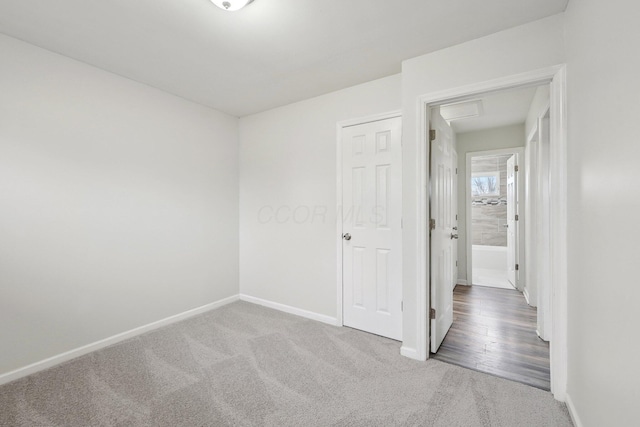 unfurnished bedroom with attic access, carpet flooring, and baseboards