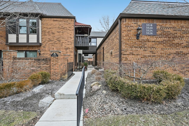 view of home's exterior with brick siding and a shingled roof