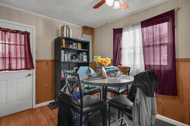 dining area with ceiling fan, wood finished floors, wainscoting, and ornamental molding