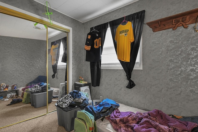 carpeted bedroom featuring a textured wall and a closet