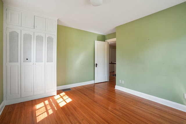 unfurnished bedroom with a closet, light wood-style flooring, visible vents, and baseboards