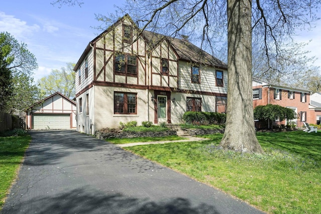 english style home with a detached garage, an outbuilding, and a front yard