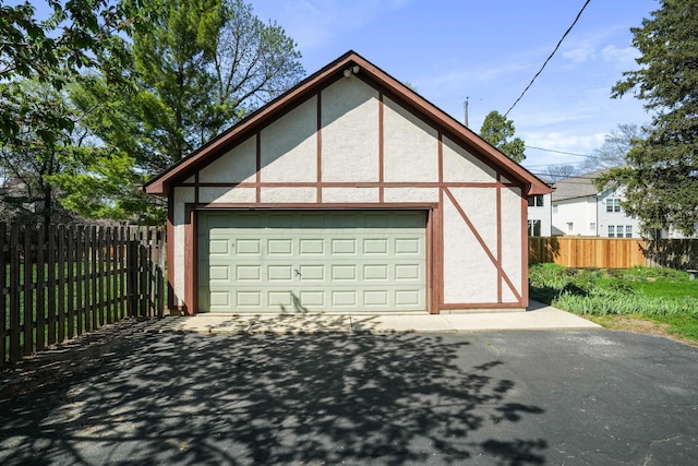 garage featuring fence and aphalt driveway