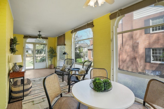 sunroom / solarium featuring a ceiling fan and outdoor dining area