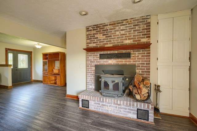 7704 Old Tarlton Pike, Circleville, OH 43113 - unfurnished living room featuring baseboards, a wood stove, wood finished floors, and a textured ceiling