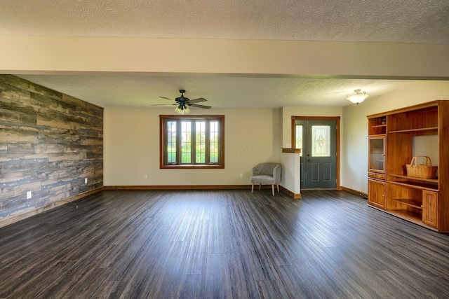 7704 Old Tarlton Pike, Circleville, OH 43113 - unfurnished living room featuring plenty of natural light, wood walls, baseboards, dark wood-style flooring, and a textured ceiling