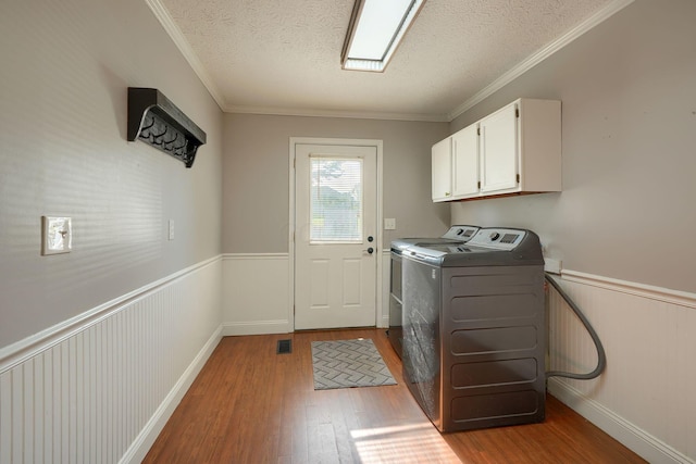 7704 Old Tarlton Pike, Circleville, OH 43113 - laundry area featuring cabinet space, wood finished floors, washer and clothes dryer, wainscoting, and a textured ceiling