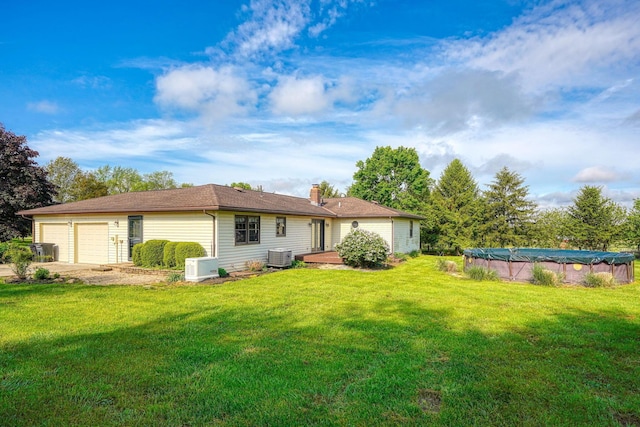 7704 Old Tarlton Pike, Circleville, OH 43113 - back of house featuring central AC, a yard, a chimney, and a garage