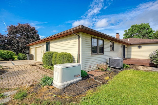 7704 Old Tarlton Pike, Circleville, OH 43113 - view of side of home with central AC unit, a deck, a chimney, an attached garage, and driveway