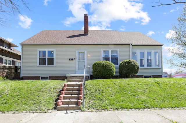 view of front of house featuring a front yard, fence, a shingled roof, and a chimney