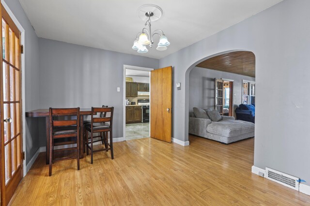 dining room featuring visible vents, baseboards, arched walkways, light wood-type flooring, and a chandelier