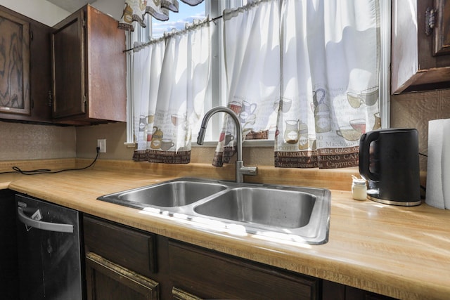 kitchen featuring a sink, light countertops, dark brown cabinetry, and dishwashing machine