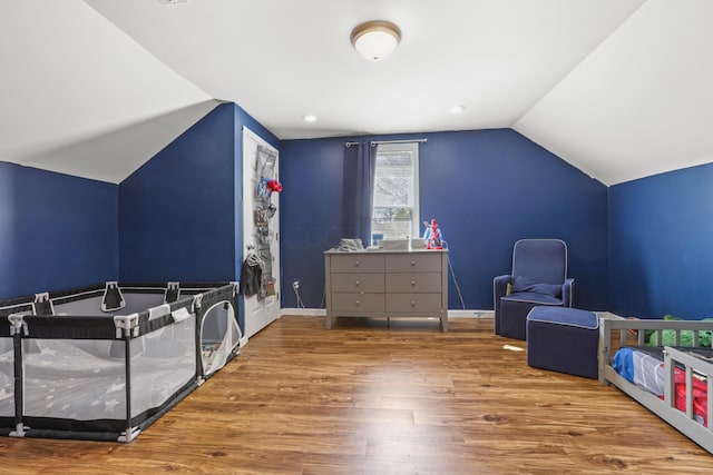 bedroom featuring lofted ceiling, baseboards, and wood finished floors