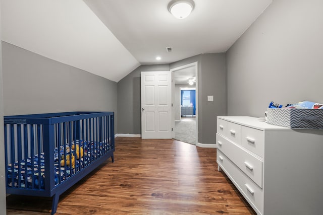 bedroom featuring lofted ceiling, baseboards, and wood finished floors