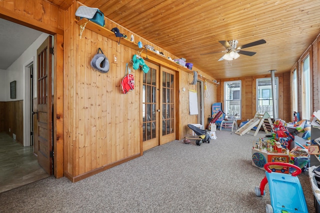 rec room featuring wood walls, ceiling fan, and wood ceiling